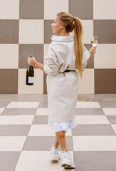 young woman tasting white wine against chessboard background