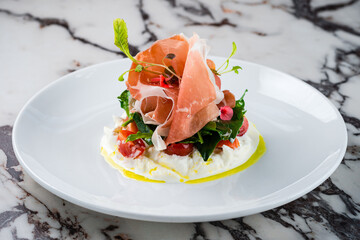 burrata cheese with Italian delicatessen salad with parma ham slices on white plate - 535338462