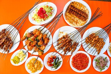 Delicious meat kebab with fresh vegetable salad served with variety of Turkish dishes and appetizers. Top view of assorted Turkish food and meze, tasty and healthy Mediterranean cuisine.