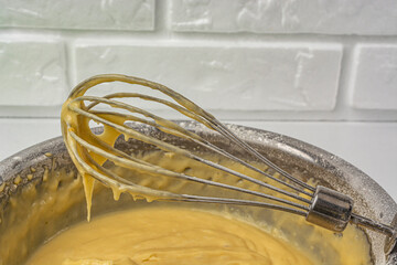 Liquid dough in an iron bowl with a whisk