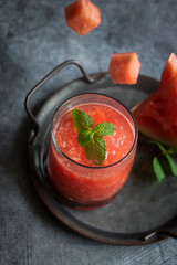 Mint, ripe watermelon, refreshing watermelon juice on a dark background.