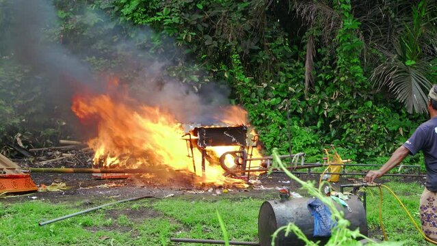 Indonesian mens on Bali island do cremation ceremony outside in nature burning man's body in coffin