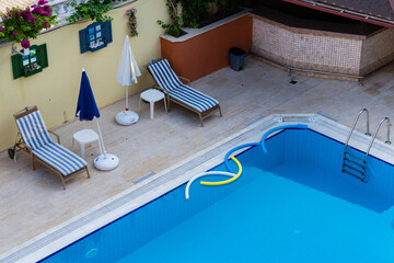 Two sunbeds on the edge of the swimming pool with clean water.