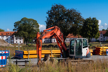 Excavator at the construction site. Orange plastic pipes.