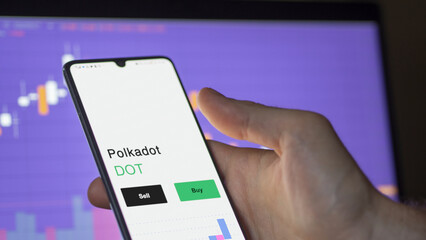 September 13th 2022, London UK. An investor's analyzing the Polkadot coin on screen. A phone shows the crypto's prices DOT to invest
