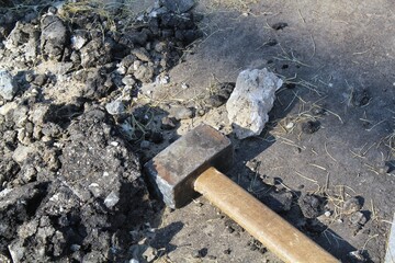 Close-up of big metal steel sledge hammer with wooden handle on cracking old pavement after road breaking. Hard work technical equipment on construction site. Industry tools. Work labor concept