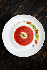 Tomato soup in a white plate on a wooden background