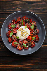 Baked tomatoes with mozzarella cheese, on a wooden background