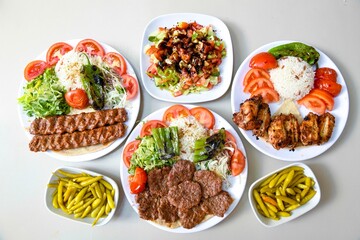 Delicious meat kebab with fresh vegetable salad served with variety of Turkish dishes and appetizers. Top view of assorted Turkish food and meze, tasty and healthy Mediterranean cuisine.