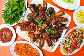 Delicious meat kebab with fresh vegetable salad served with variety of Turkish dishes and appetizers. Top view of assorted Turkish food and meze, tasty and healthy Mediterranean cuisine.