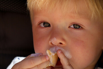 cute blond child eating ice cream close up portrait