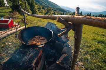 cast iron tourist cookware. View of the Carpathian Mountains. Summer day. Campfire. Tourism and...
