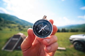 Travel magnetic compass male hand on background of mountain ridge in summer outdoor, point of view....