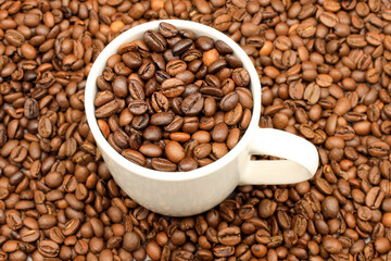 White cup filled with coffee beans on rustic wooden table. Top view. Coffee concept for cafes