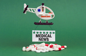 On a green surface, an ambulance helicopter, pills and a white sign with the inscription - MEDICAL...