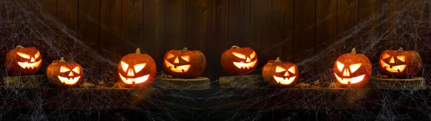 Scary Halloween celebration holiday card - Spooky carved pumpkins, spider web and dust on dark wooden wall wood background banner panorama