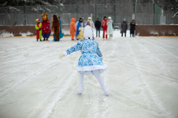 Child on skates. Ice rink in winter. Active lifestyle in winter. Girl is engaged in figure skating.