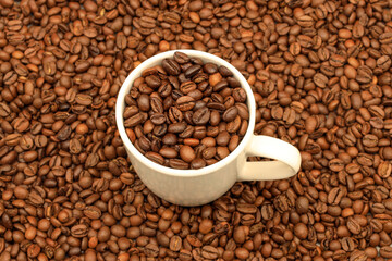 White cup filled with coffee beans on rustic wooden table. Top view. Coffee concept for cafes
