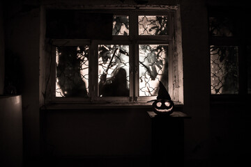 Scary Halloween pumpkin in the mystical house window at night or halloween pumpkin in night on room...