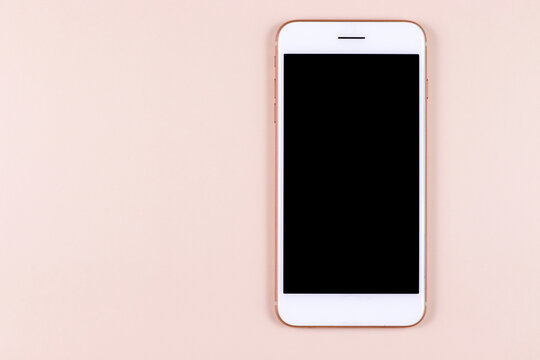 White phone smartphone with black screen lies on a pastel pink background. Good quality