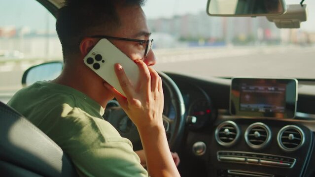 Young man driver close-up, calling, using phone. Car sharing concept, vehicle and transport. Asian happy guy driving, sitting in car. Traveling by automobile.