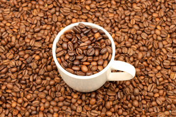 White cup filled with coffee beans on rustic wooden table. Top view. Coffee concept for cafes