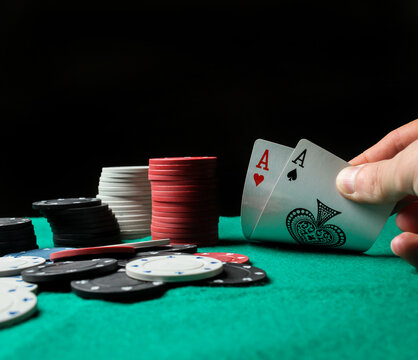 two aces in the hands of a close-up. An concept Image of a poker table. two aces, two playing cards and poker chips on the green casino table, on a black background. success in gambling. soft focus