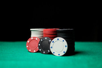 Poker game concept. Casino Concept for business risk chance good luck or gambling. Stack of Poker chips, poker chips stack on a green gaming poker table, black background. soft focus