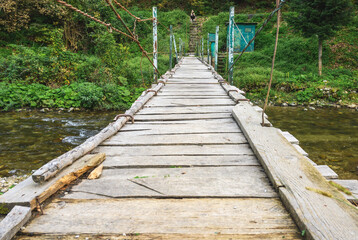 Rudimentary wooden bridge over a mountain river. Wooden bridge over the water.