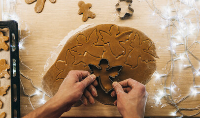 Men's hands knead the dough. The chef prepares ginger. Christmas cookies on the table with cooking flour.