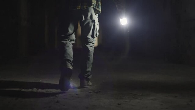 The man's legs walk along a mystical tunnel. A man with a flashlight in the dark. The guy lights his way. High quality 4k footage