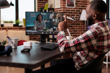 Male freelancer using online teleconference call to attend business meeting on remote videoconference. Talking on videocall conference with webcam and computer, working on pc with internet.