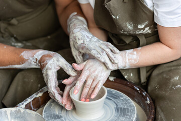 Romantic unusual date in the pottery. Man and woman in love doing clay jar together, holding hands