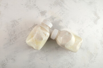 Two bloated swollen bottles with sour milk or expired spoiled dairy product with dangerous bacteria microbes. Concept - Improper storage of food. Poisoning with expired fermented milk products