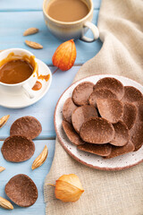 Chocolate chips with cup of coffee and caramel on a blue wooden background. side view, close up, selective focus.