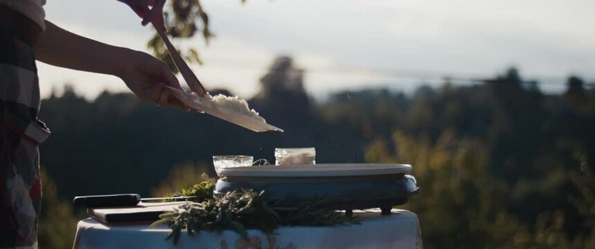 Female cooking risotto stirs onion in a pan outdoor close up flares
