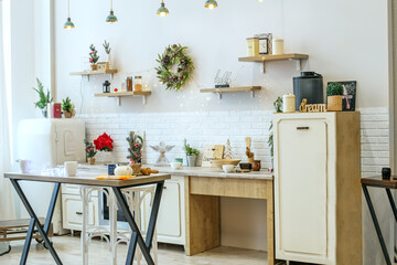 Bright kitchen interior with Christmas decor and Christmas wreath. Kitchenware.