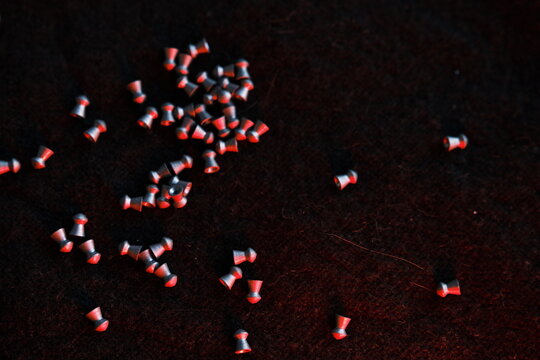 air gun pellets on darck cloth background with red light for illumination