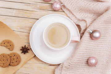 A cup of coffee latte, homemade cookies and Christmas balls on a knitted sweater. Winter holidays concept. Top view, flat lay