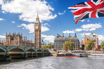 Fototapeta na wymiar Big Ben with bridge over Thames and flag of England against blue sky in London, England, UK