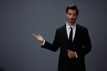 Man businessman smiling happily with his teeth raised hands up in a business suit with tie on a dark gray background