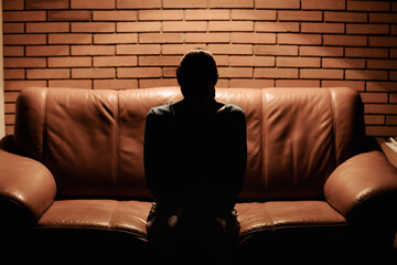 Unrecognizable woman silhouette sitting in a dark room 