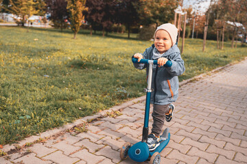 Kid play outdoors with kick scooter. Active leisure and outdoor sport for child. Happiness and...