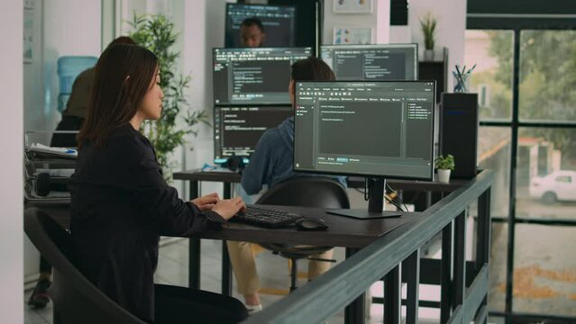 Asian software engineer working with user interface on computer screen to develop new security firewall and html script. Database programer writing code with server algorithms on terminal window.