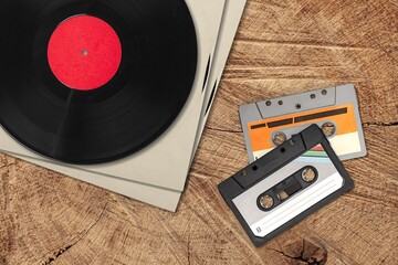 Vinyl records, cassette tapes and cassette recorder on table. Retro music style. 80s music party....