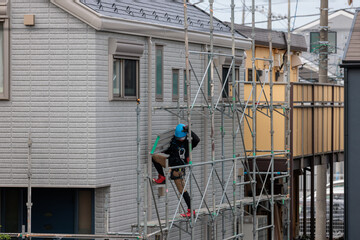 住宅の外壁工事が終了し足場を解体する作業員