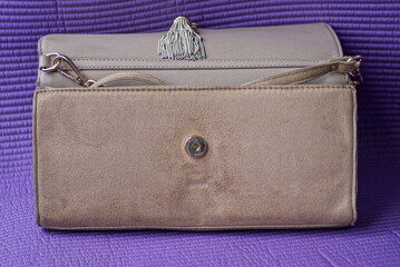 one light brown open wallet made of suede and leather stands on a purple table