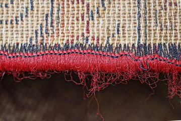 part of a brown floor carpet with an overlock red thread edge