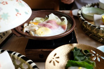 Japanese hot pot (nabe) with cabbage, enoki mushrooms, bacon, a poached egg as part of a traditional kaiseki breakfast at a ryokan in Sengokuhara, an onsen town in Hakone — Kanagawa Prefecture, Japan