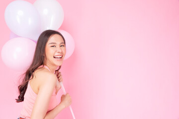 Obraz na płótnie Canvas Excited cheerful asian woman holding balloons and hands beside mouth smiling with toothy standing over isolated pink background. Joyful teenager girl with pastel balloons shocked amazed expression.